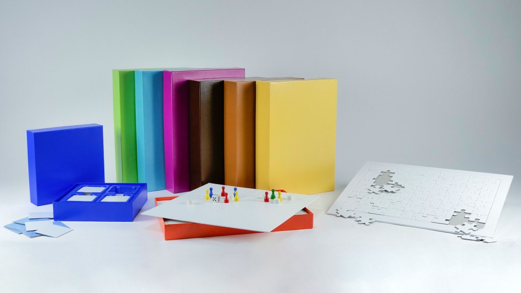 Eine Darstellung des Produktsortiments, bestehend aus Schachteln und Blanko Spielen