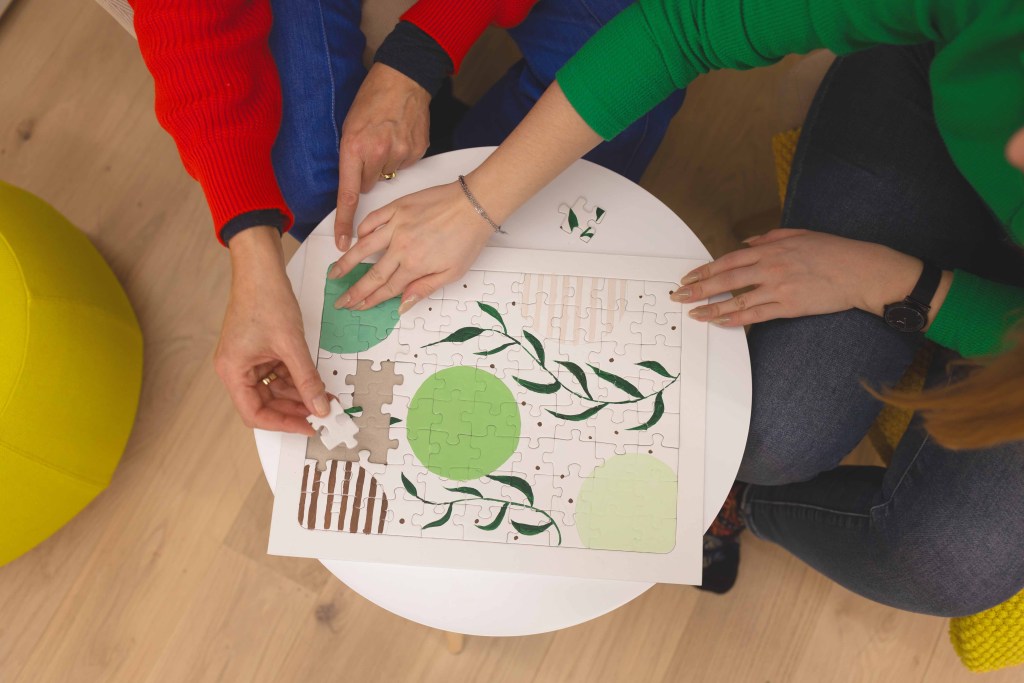 Zwei Frauen puzzlen ein selbst gemaltes Puzzle