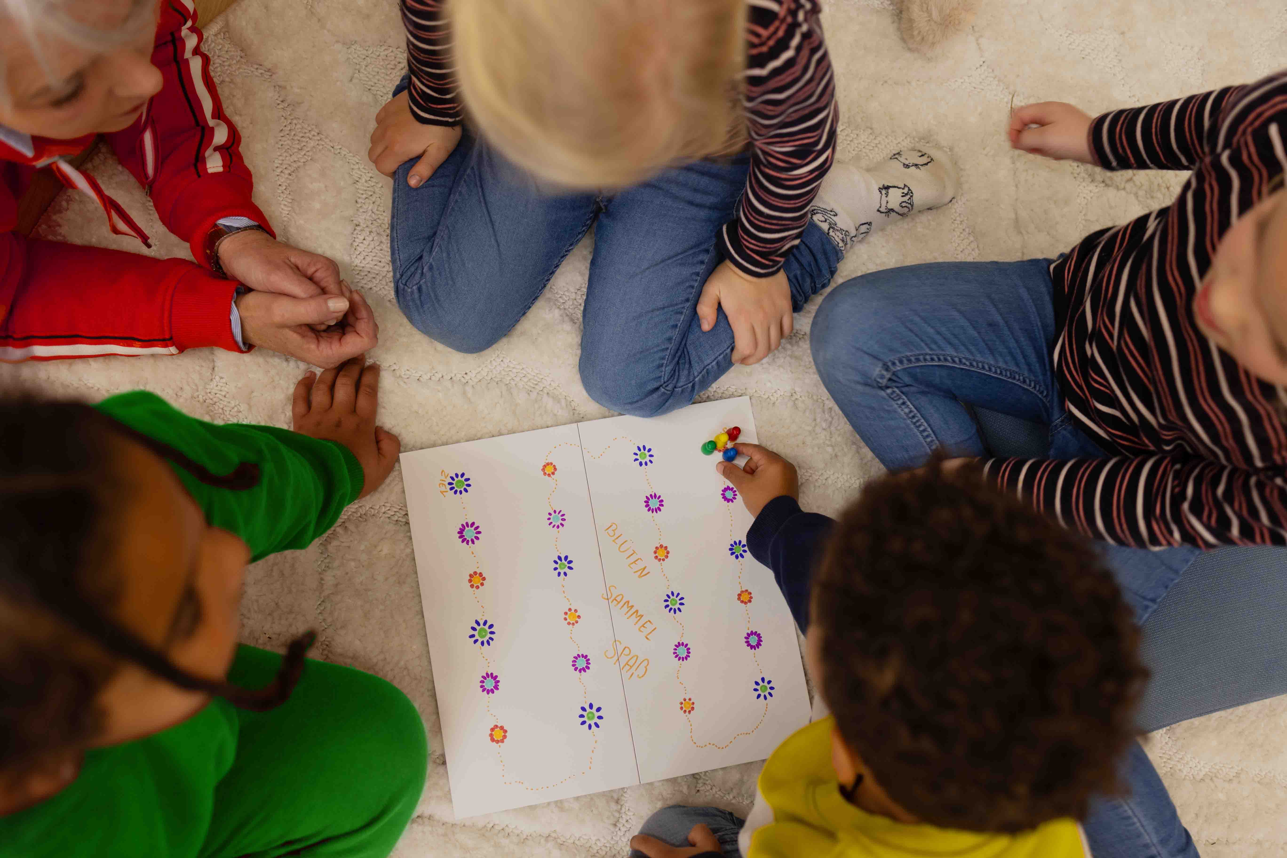 Vier Kinder und eine Frau spielen ein selbst gemachtes Spiel